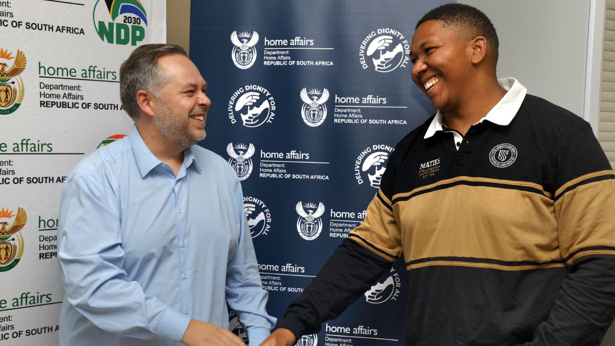Home Affairs minister Leon Schreiber gives !Khūboab Oedasoua Lawrence his smart ID card.